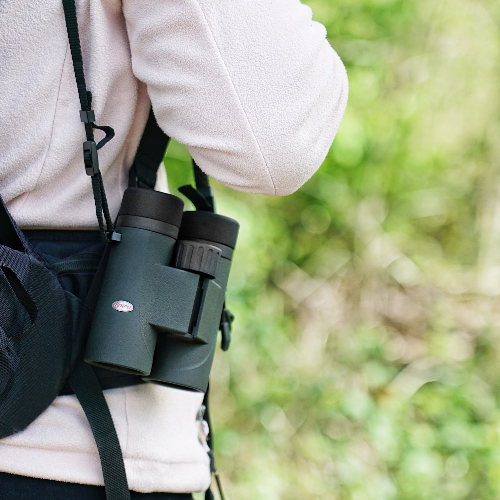 Birdwatcher carrying Kowa SV III binoculars naturally at her side on a woodland walk