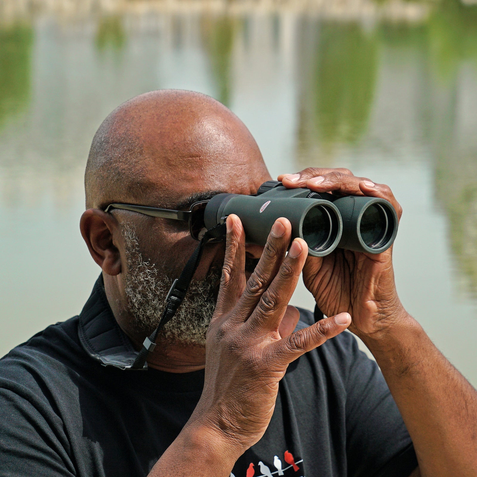 Birdwatcher viewing through Kowa SV III binoculars beside water
